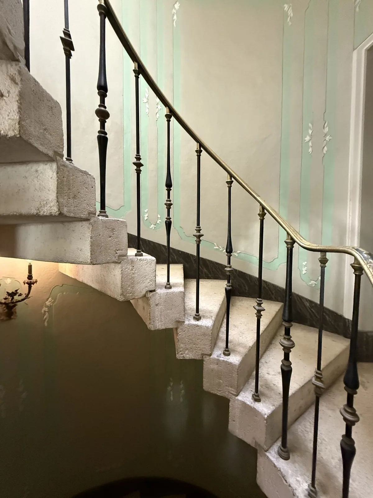 Raw concrete staircase with ironwork railing against a hand-painted wall