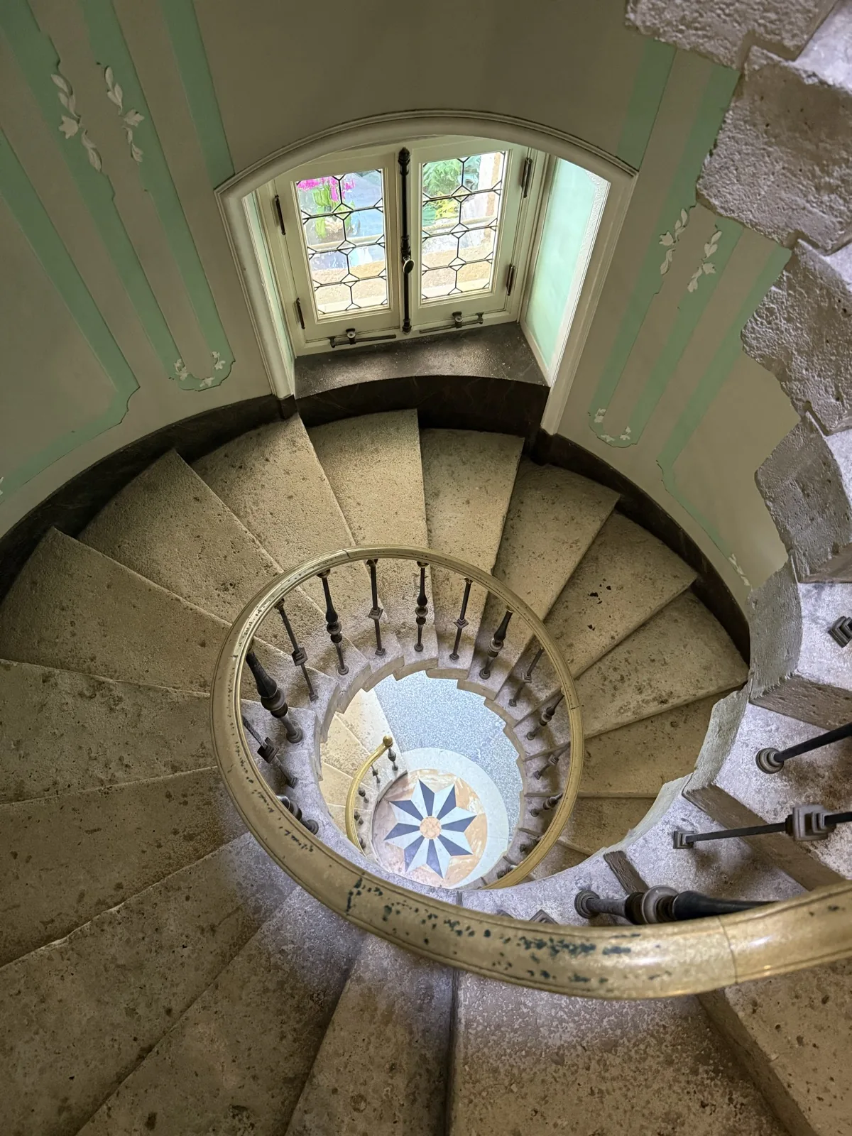 Spiral stone staircase with wrought-iron railing and stained glass — timeless craftsmanship