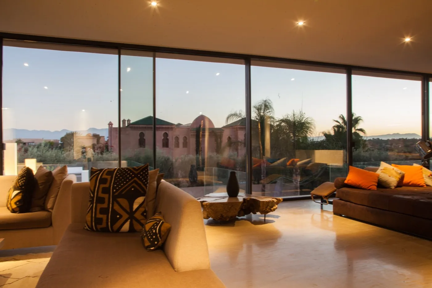 Salon d'une villa à Marrakech avec grandes baies vitrées en menuiserie aluminium ouvertes sur le jardin et l'Atlas (réalisation Technal by LMI-64)