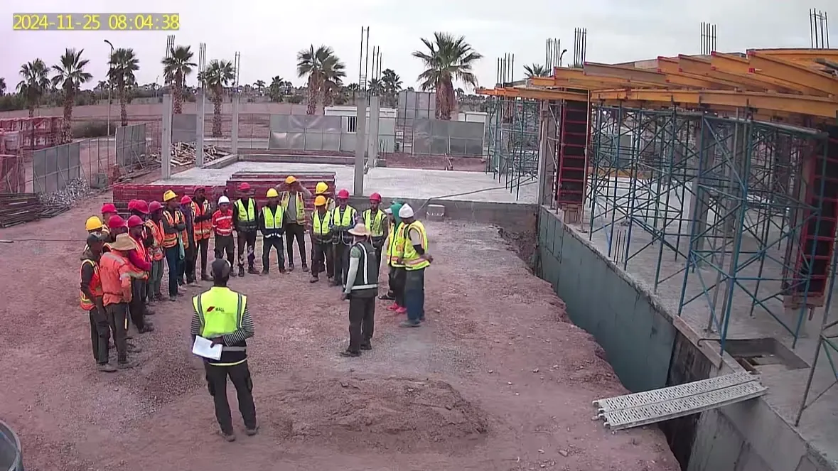 Caméra de chantier WALL Construction en temps réel : briefing sécurité du matin, équipes en gilets et casques, sous-sol et voiles béton à Marrakech
